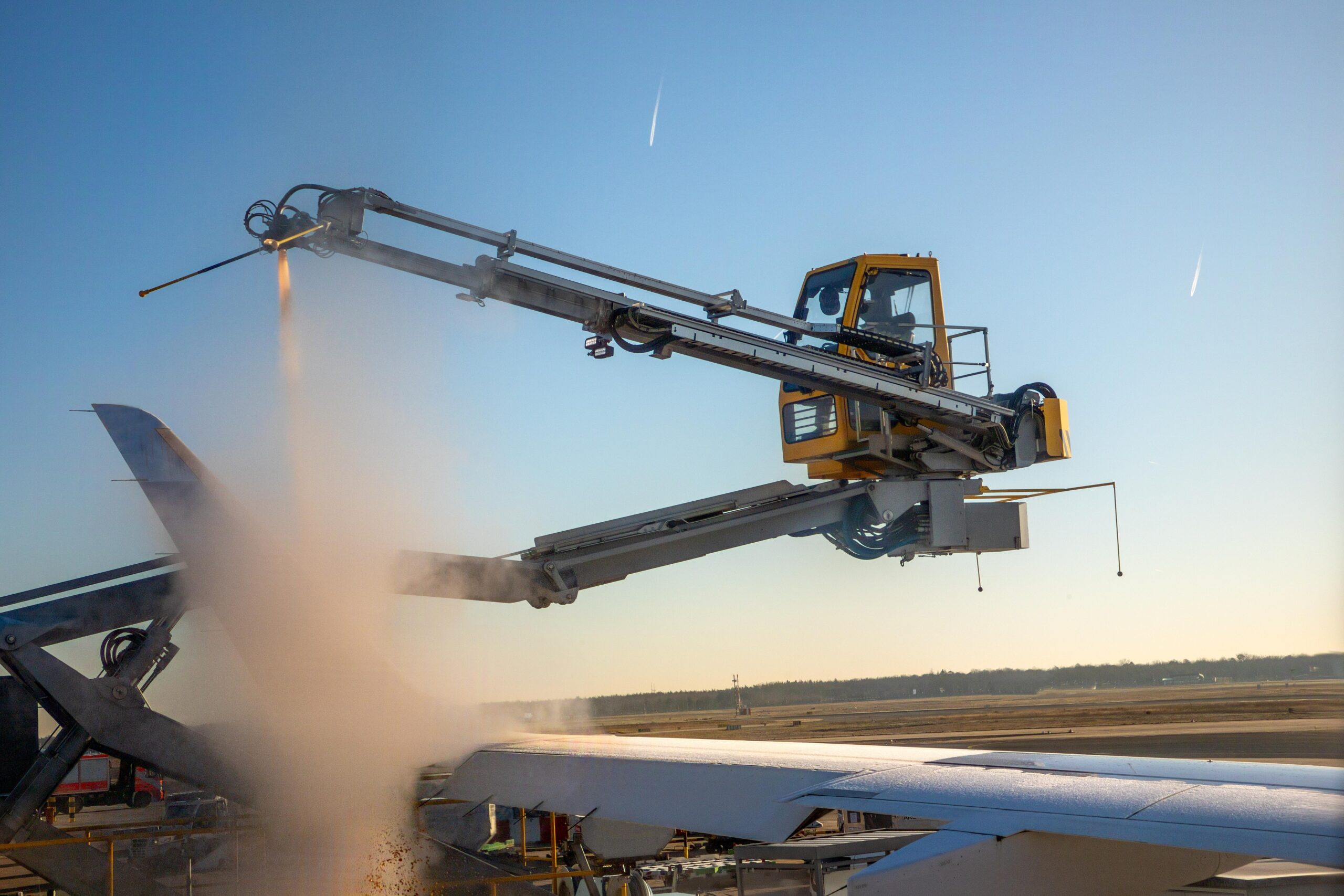 Aircraft deicing truck spraying fluid on airplane wing