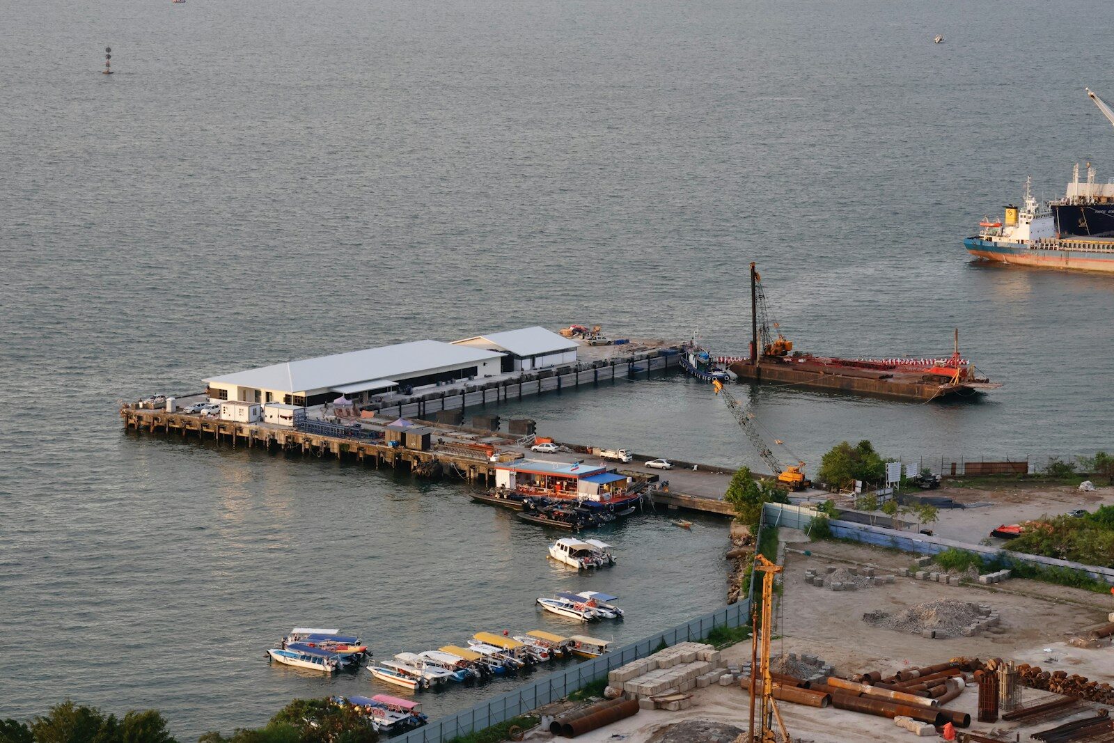 Boats docked at a pier with a large ship nearby