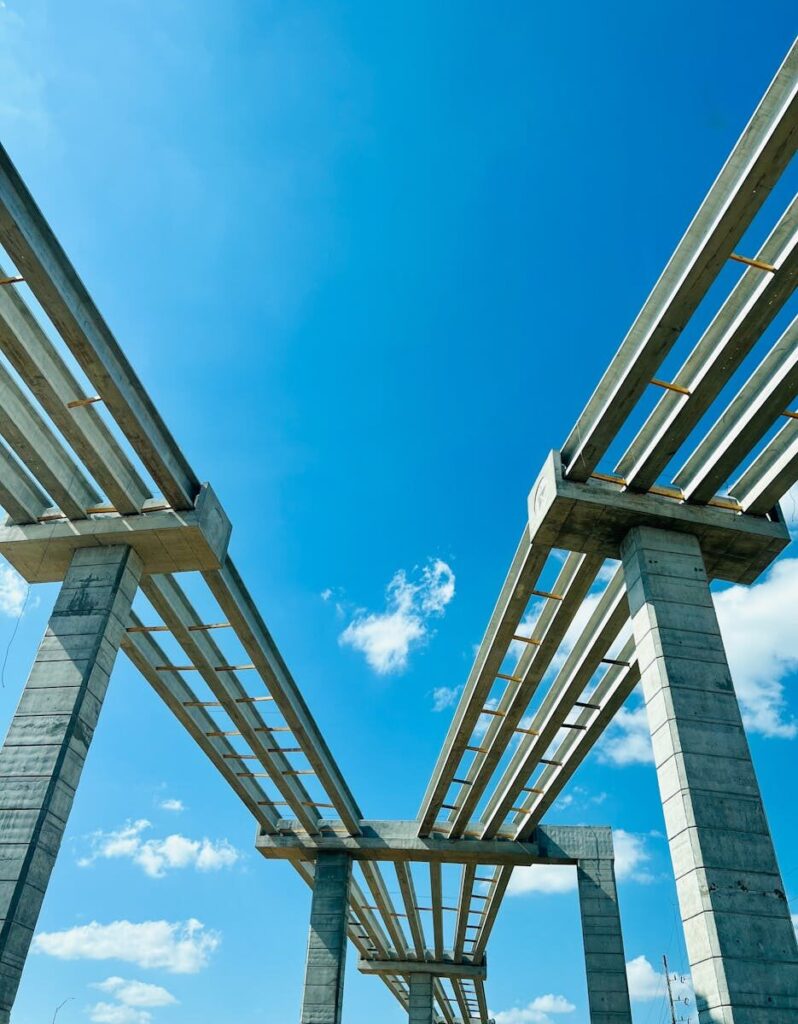 Low-angle view of a modern concrete bridge under construction with a clear blue sky backdrop, ideal for engineering themes.