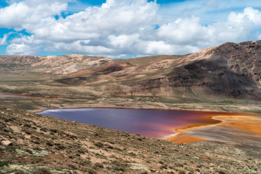 a lake surrounded by mountains under a cloudy blue sky